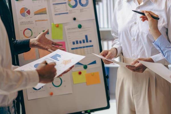 People discussing documents, charts in front of a clipboard